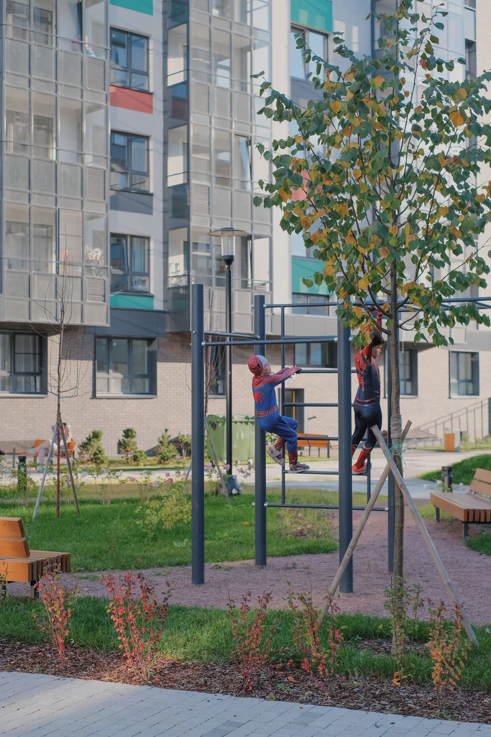 Дети играют на уличном спортивном комплексе во дворе жилого квартала